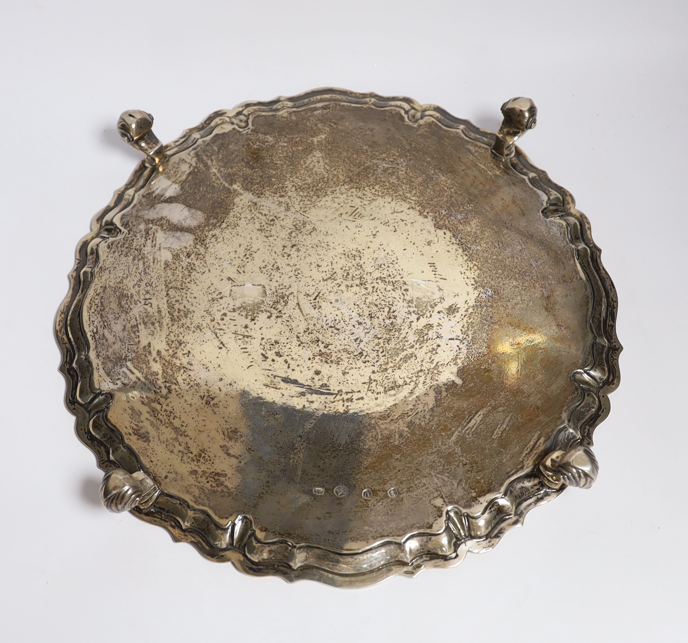 A large George II silver shaped circular salver, with pie crust border and engraved armorial, on four scroll feet, by John Tuite, London, 1735, diameter 36.6cm, 43.1oz.